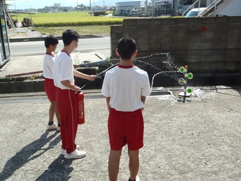 水消火器による消火訓練を実施する中学生の写真