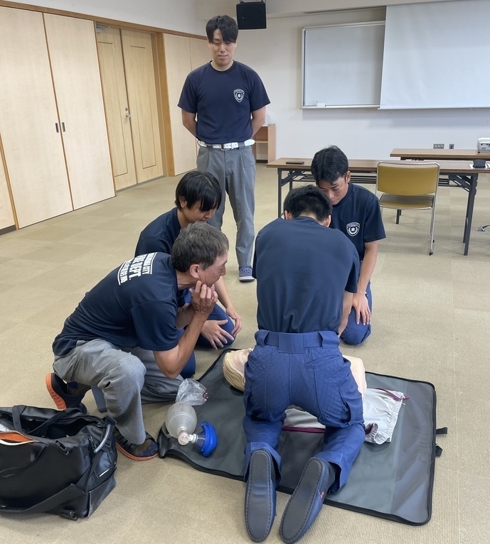 初任教育中の学生が救急救命士に心肺蘇生法を教えてもらいながら実践している写真。