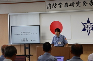 写真：林 副士長が登壇し発表している。